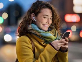 Mulher sorridente ao telemóvel com auriculares